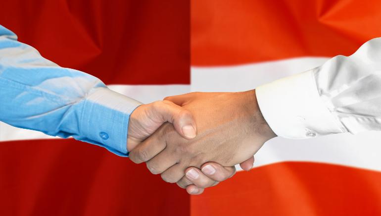 An handshake and Danish flag on the background